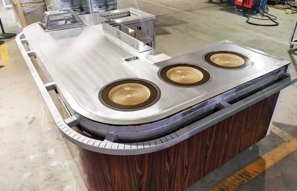 Industrial stainless teppanyaki unit on factory floor with protective film and specification label