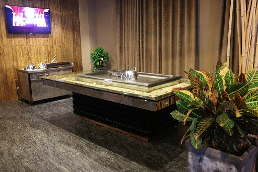 Teppanyaki grill table with stainless cooking surface in a warm wood and stone dining interior