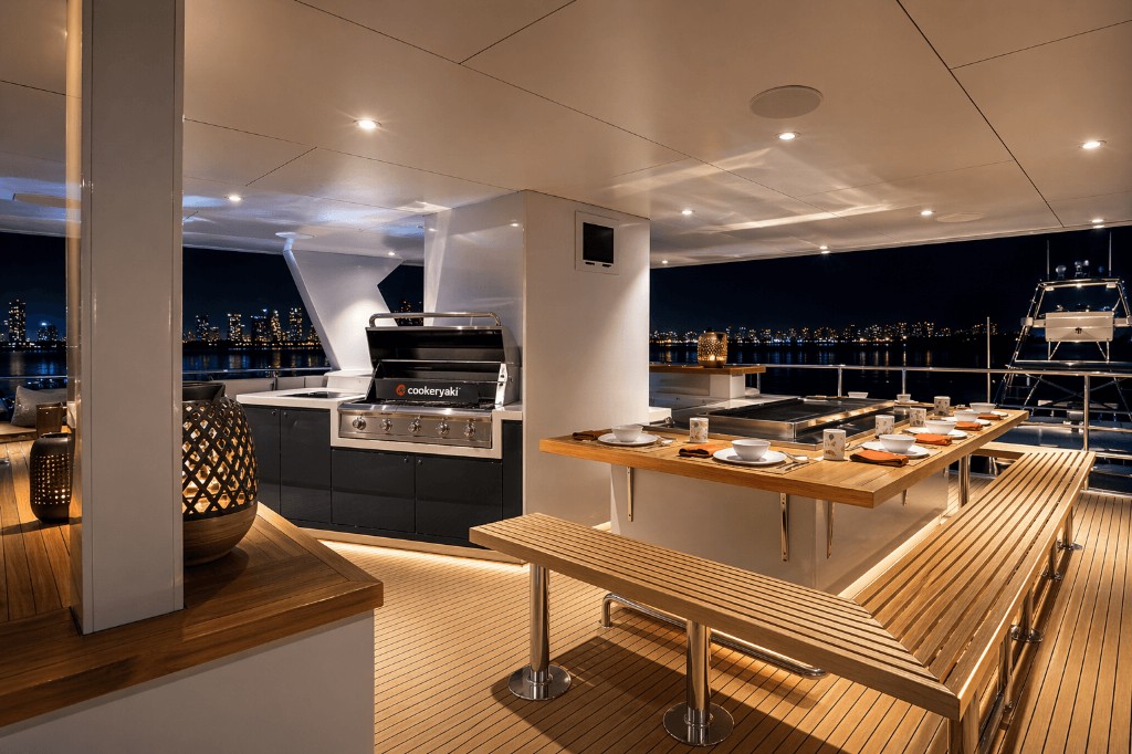 Outdoor teppanyaki dining table on a yacht deck at night with city lights across the water