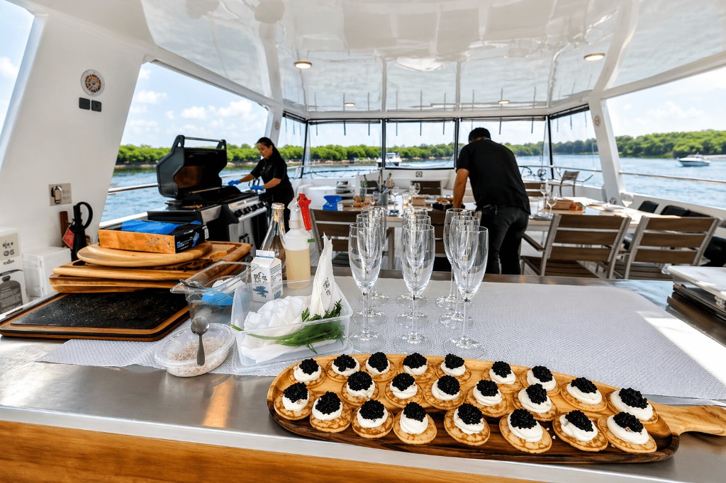Yacht catering spread with appetizers and champagne flutes beside an outdoor grill station